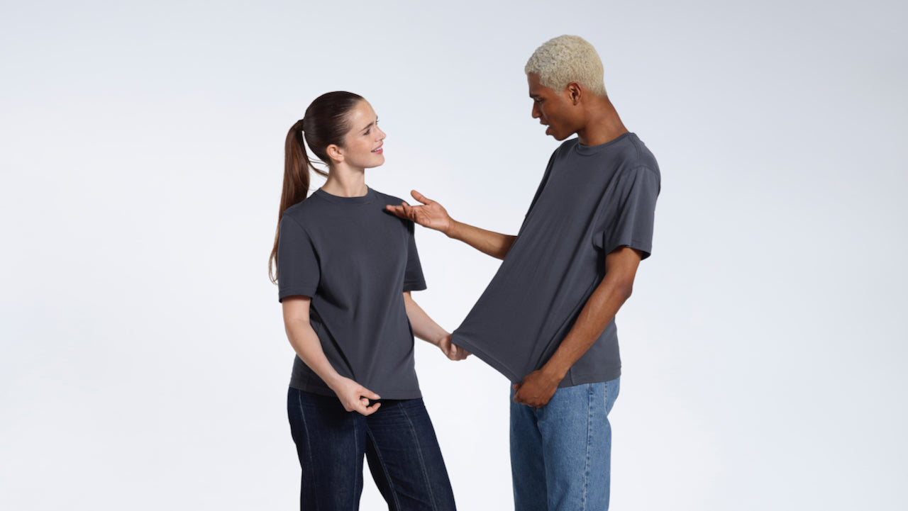 A man and woman looking at eachother talking, modelling plain dark grey matching short sleeve organic cotton t shirts.