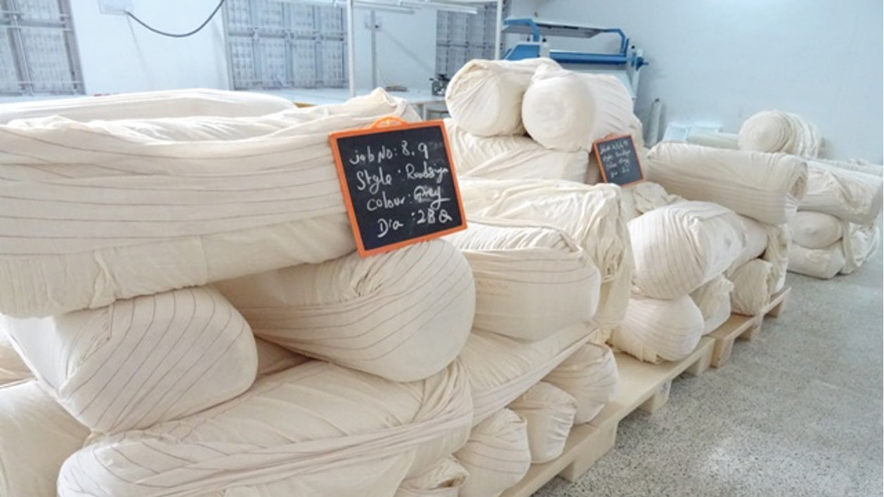 A large amount of white fabric in a storage area in an ethical factory in India.