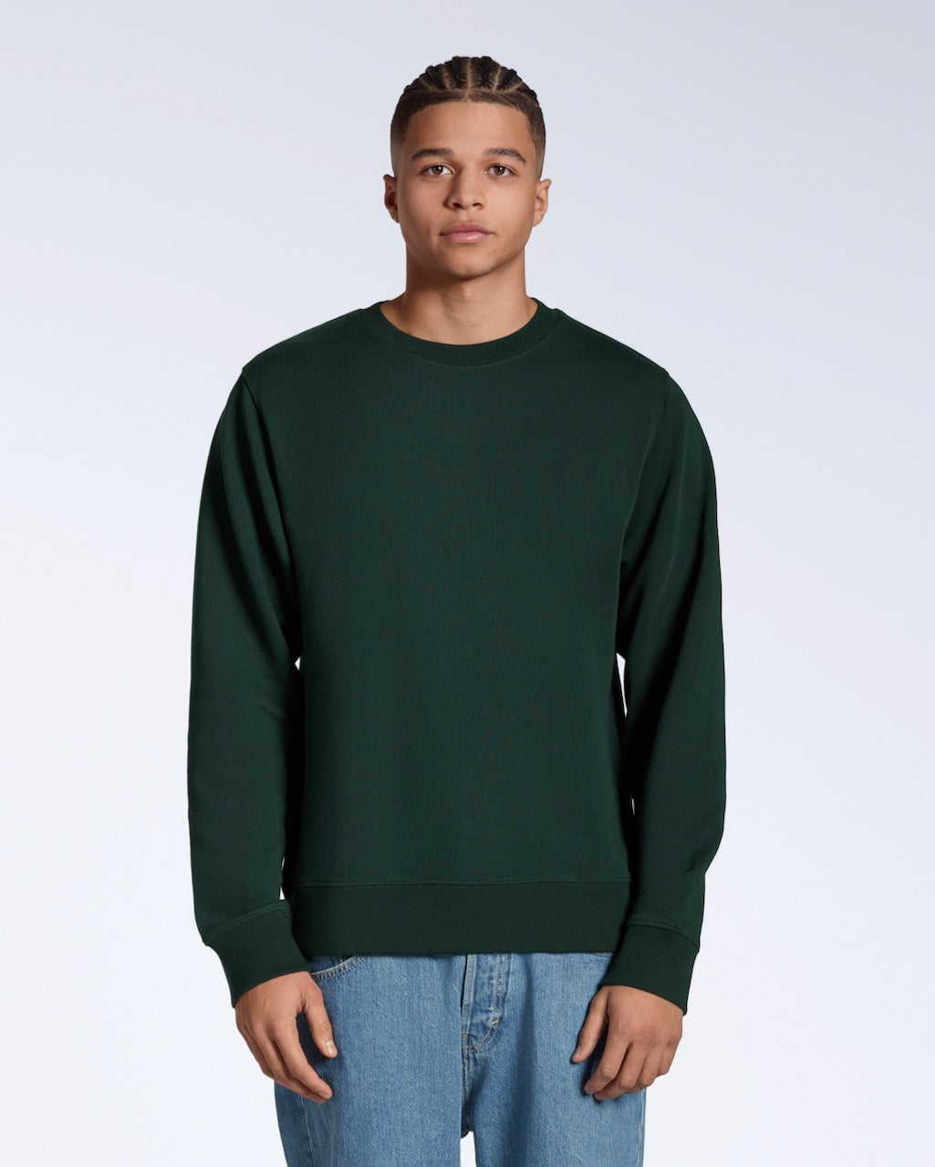 A man face on looking into the camera with his arms by his side, modelling a plain dark green french terry organic cotton sweatshirt.