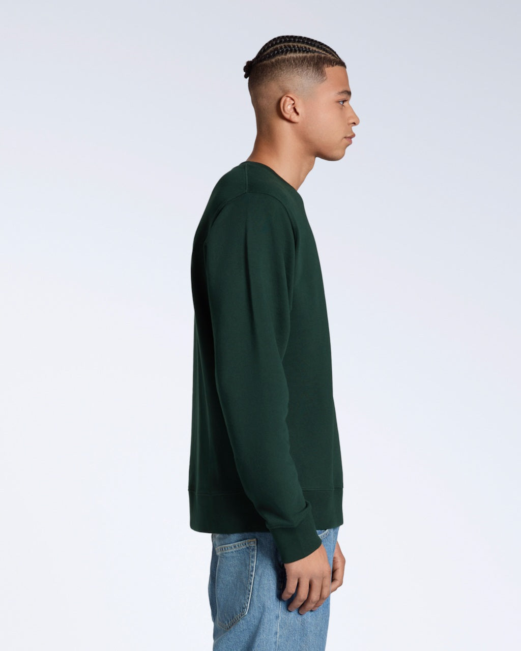 A man facing side on, modelling a plain dark green french terry organic cotton sweatshirt.
