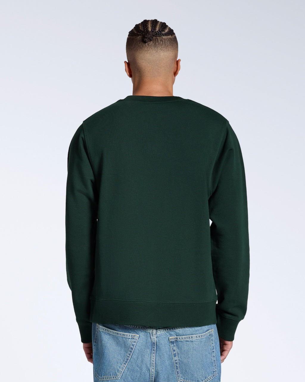 A man facing away from the camera, showing the back of his plain dark green french terry organic cotton sweatshirt.