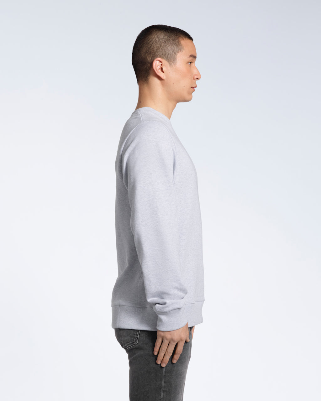 A man facing side on, modelling a plain grey french terry organic cotton sweatshirt.