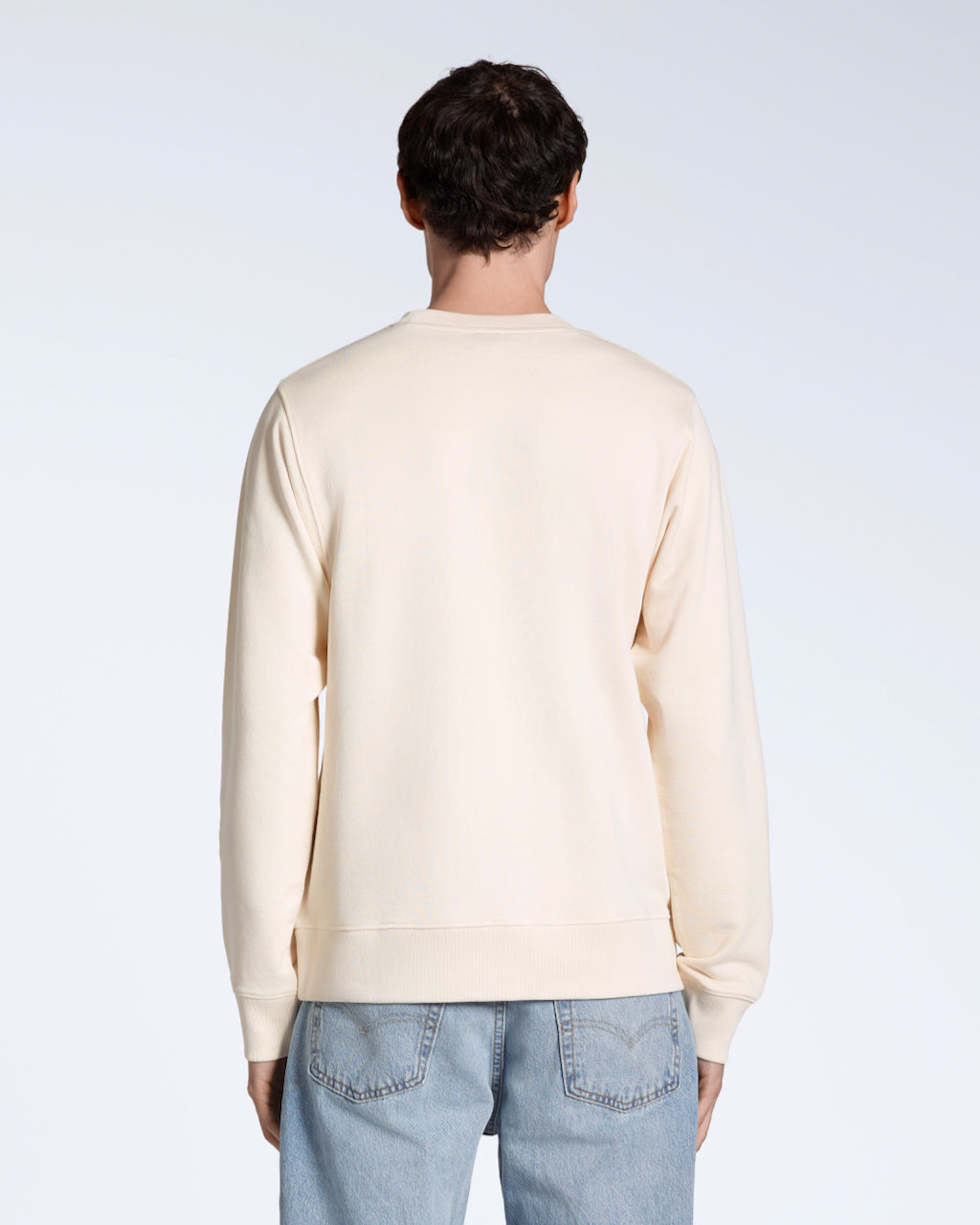 A man facing away from the camera, modelling a plain natural coloured, organic cotton sweatshirt.