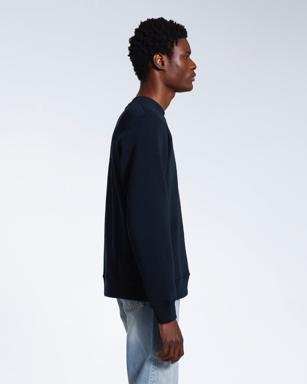A man facing side on, modelling a plain navy french terry organic cotton sweatshirt.