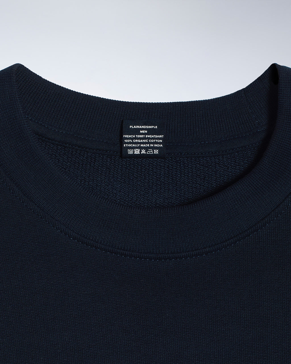 A close up of an neck label in a men's navy organic cotton sweatshirt.