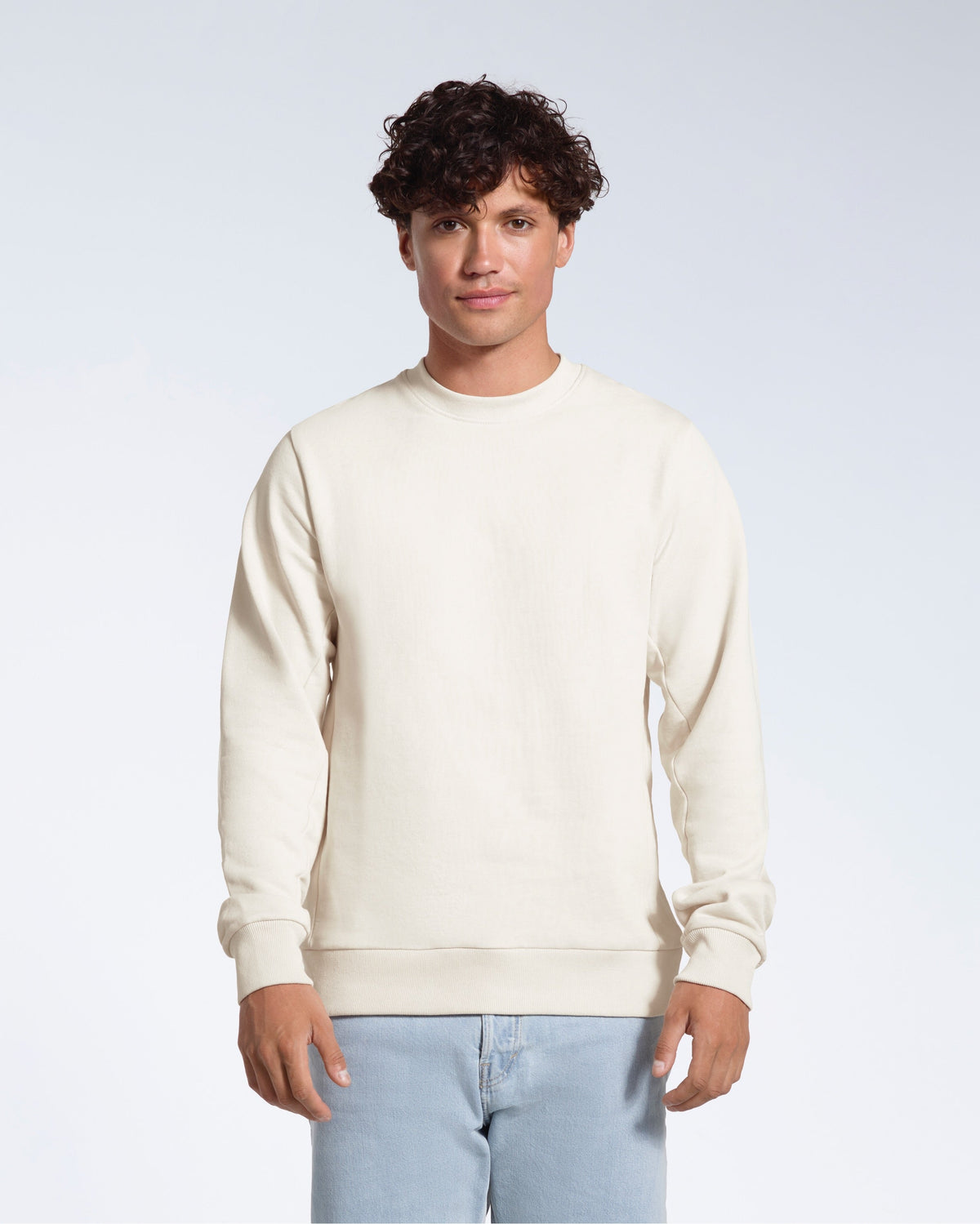 A man face on looking into the camera with his arms by his side, modelling a plain off white french terry organic cotton sweatshirt.