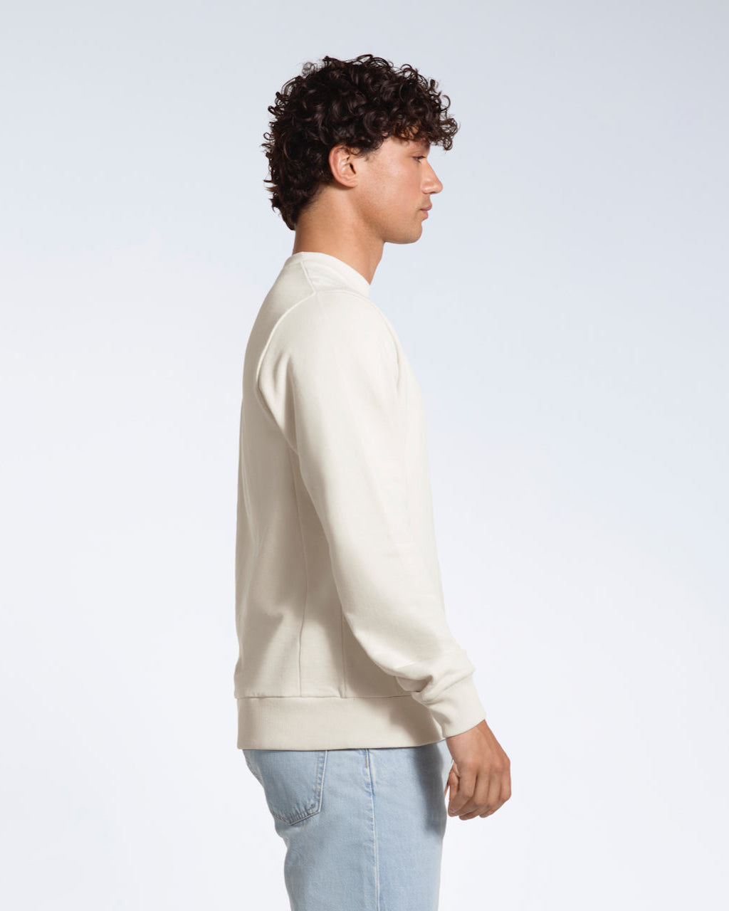 A man facing side on, modelling a plain off white french terry organic cotton sweatshirt.