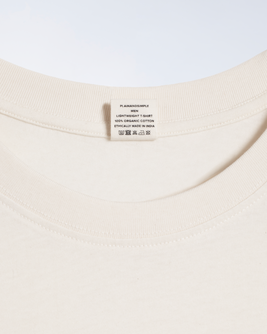 A close up of the neck label in a natural coloured, lightweight, organic cotton t shirt.