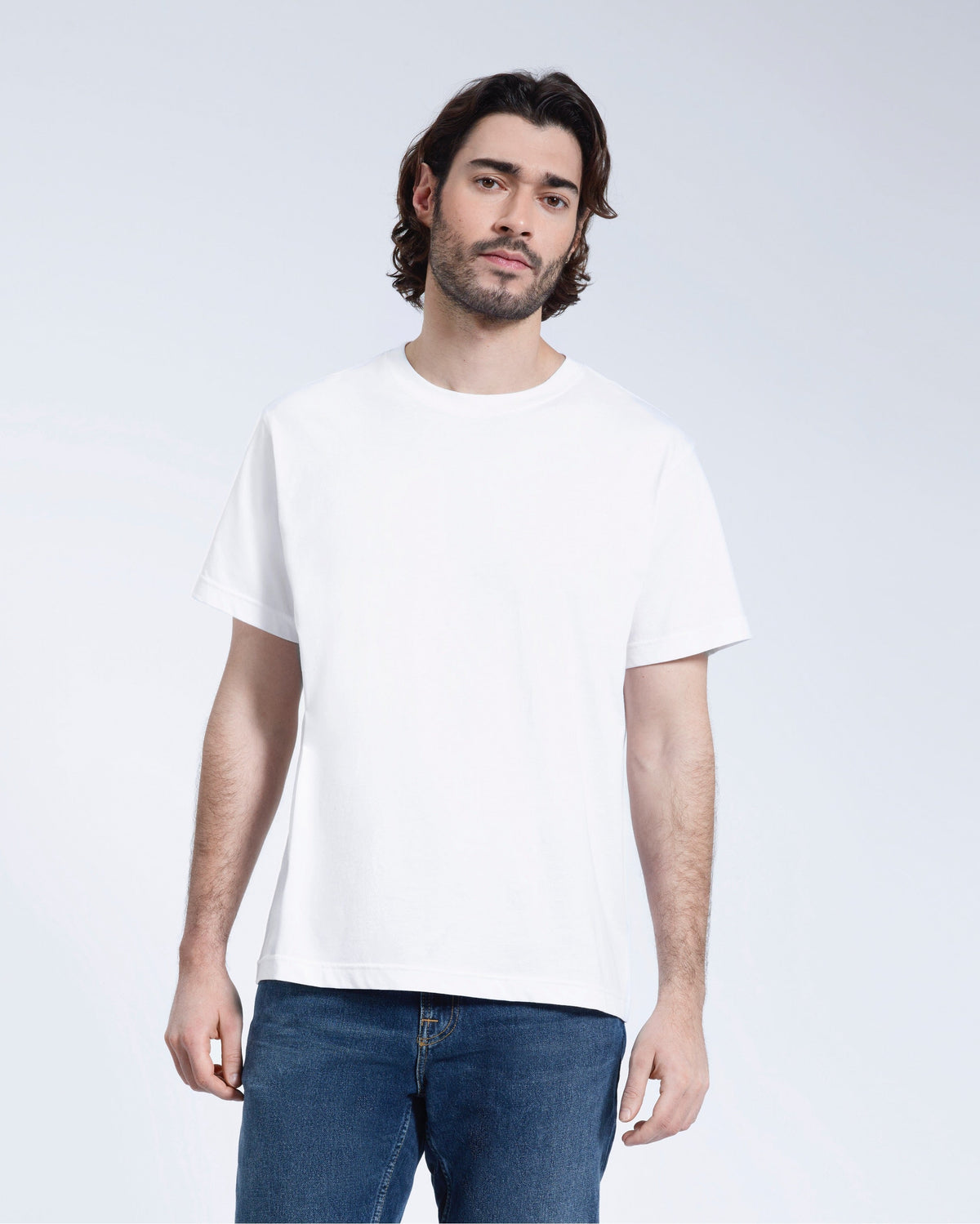 A man face on looking into the camera with his arms by his sides, modelling a plain white short sleeve organic cotton t shirt.