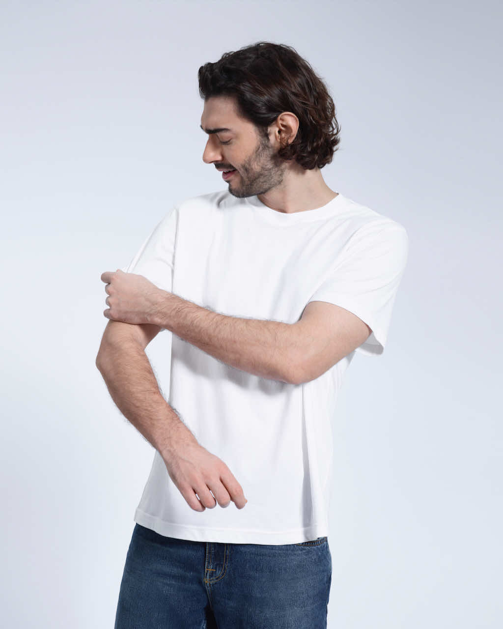 A man looking down and touching his sleeve, modelling a plain white short sleeve organic cotton t shirt.