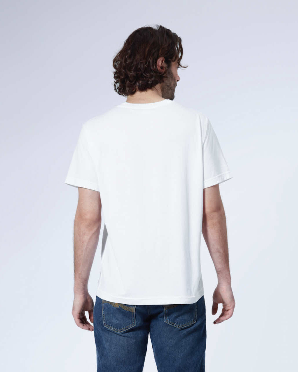 A man facing away from the camera with his arms by his side, modelling a plain white short sleeve organic cotton t shirt.
