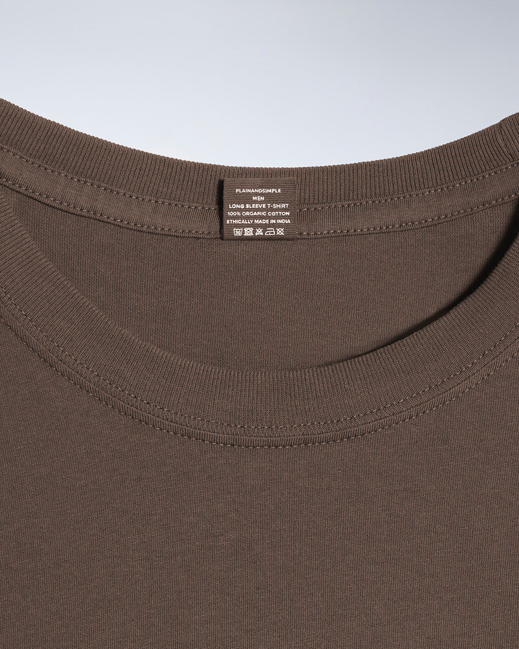 A close up of a neck label in a men's dark khaki long sleeve crew neck organic cotton t shirt.