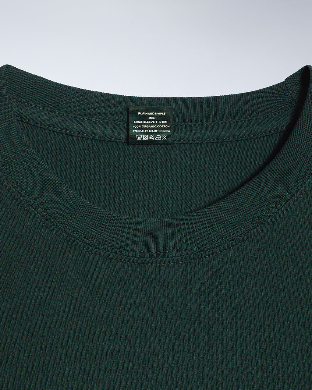 A close up of a neck label in a men's green long sleeve crew neck organic cotton t shirt.
