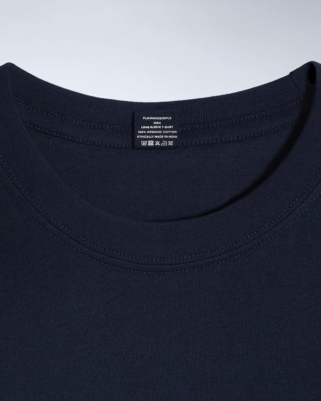 A close up of a neck label in a men's dark navy sleeve crew neck organic cotton t shirt.