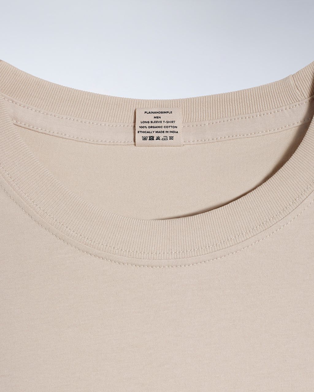A close up of a neck label in a men's stone long sleeve crew neck organic cotton t shirt.