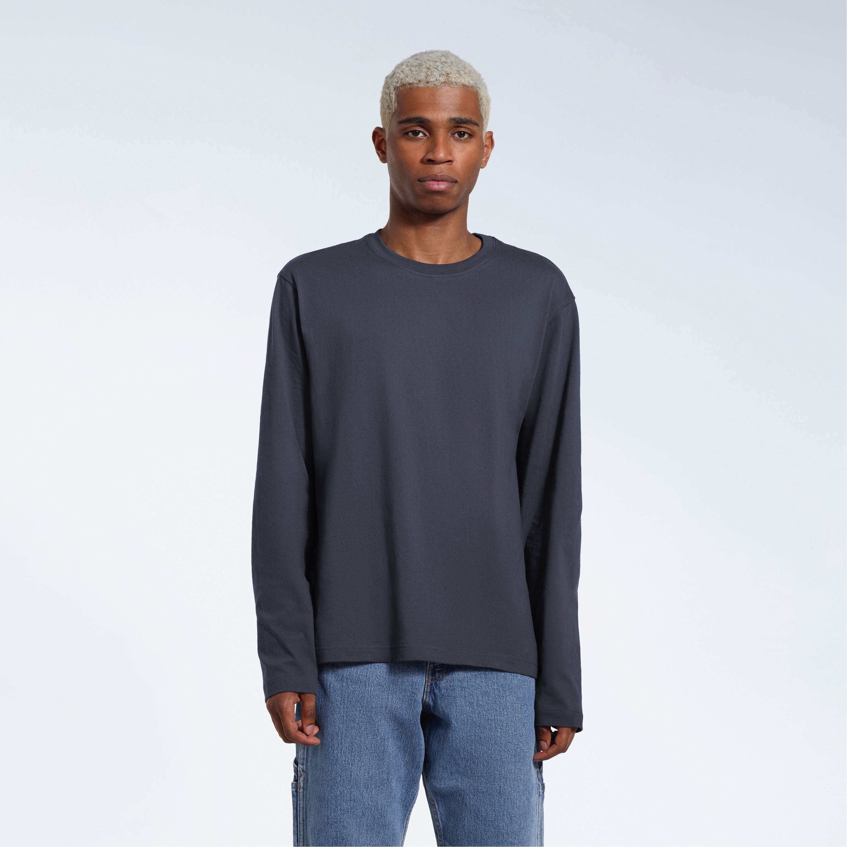 A man standing front on with his arms by his sides, modelling a plain dark grey long sleeve organic cotton t shirt.