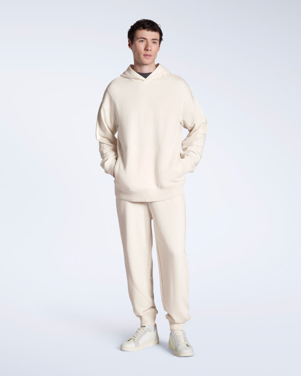 A man looking at the camera with his hand in his pocket, modelling a pair of dark grey organic cotton joggers.