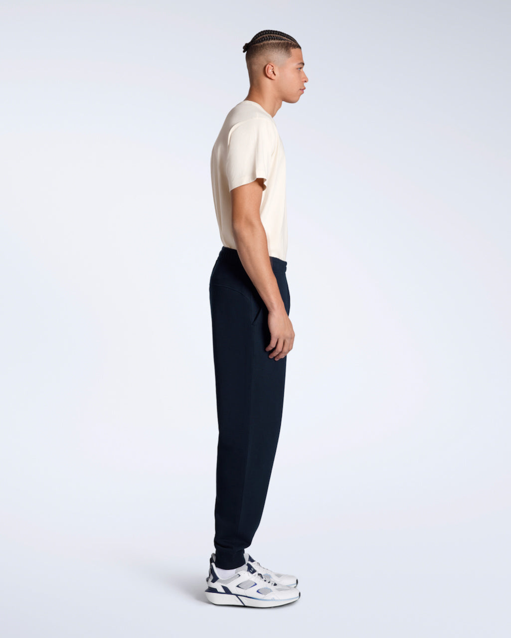 A man facing side on with his arms by his sides, modelling a pair of navy organic cotton joggers.