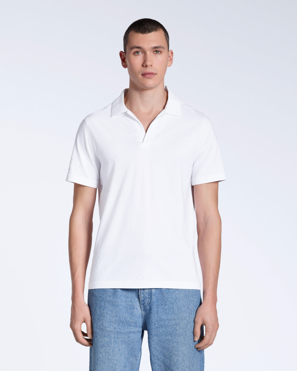 A man facing front on, modelling a plain white, short sleeve organic cotton polo shirt.