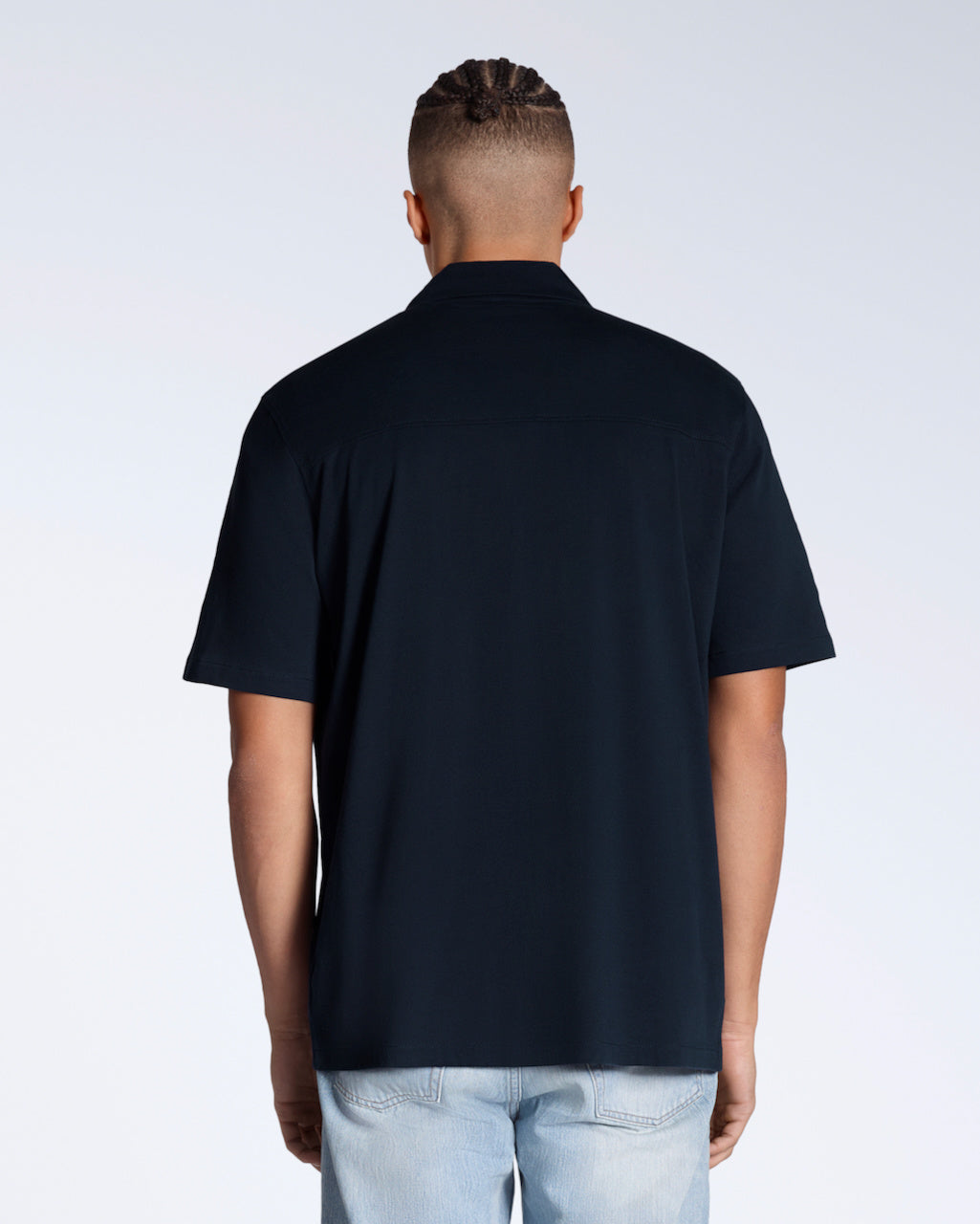 A man facing away from the camera, modelling a plain navy, organic cotton resort shirt.