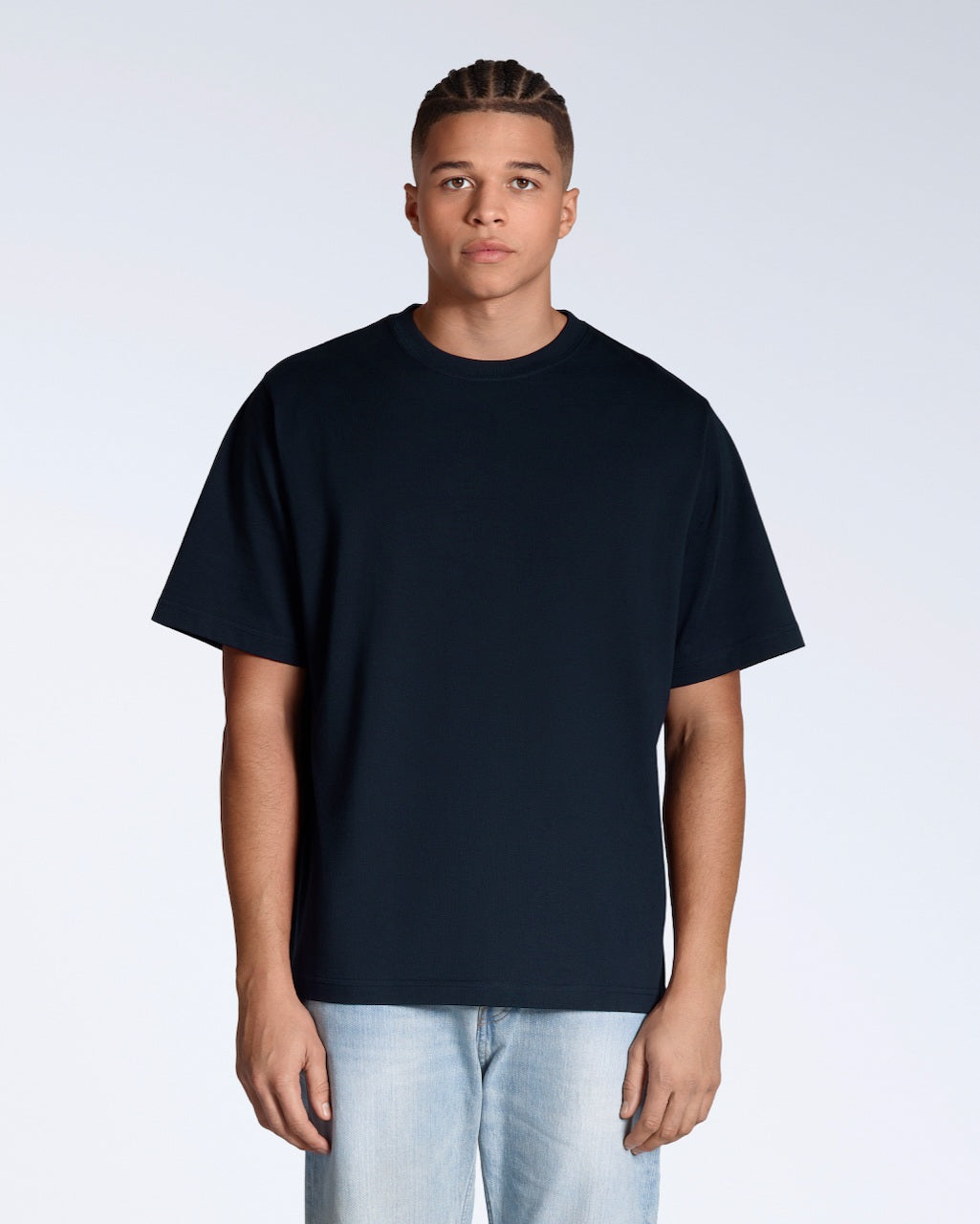 A man facing front on, looking into the camera with his arms by his side, modelling a plain navy, organic cotton, oversized t shirt.