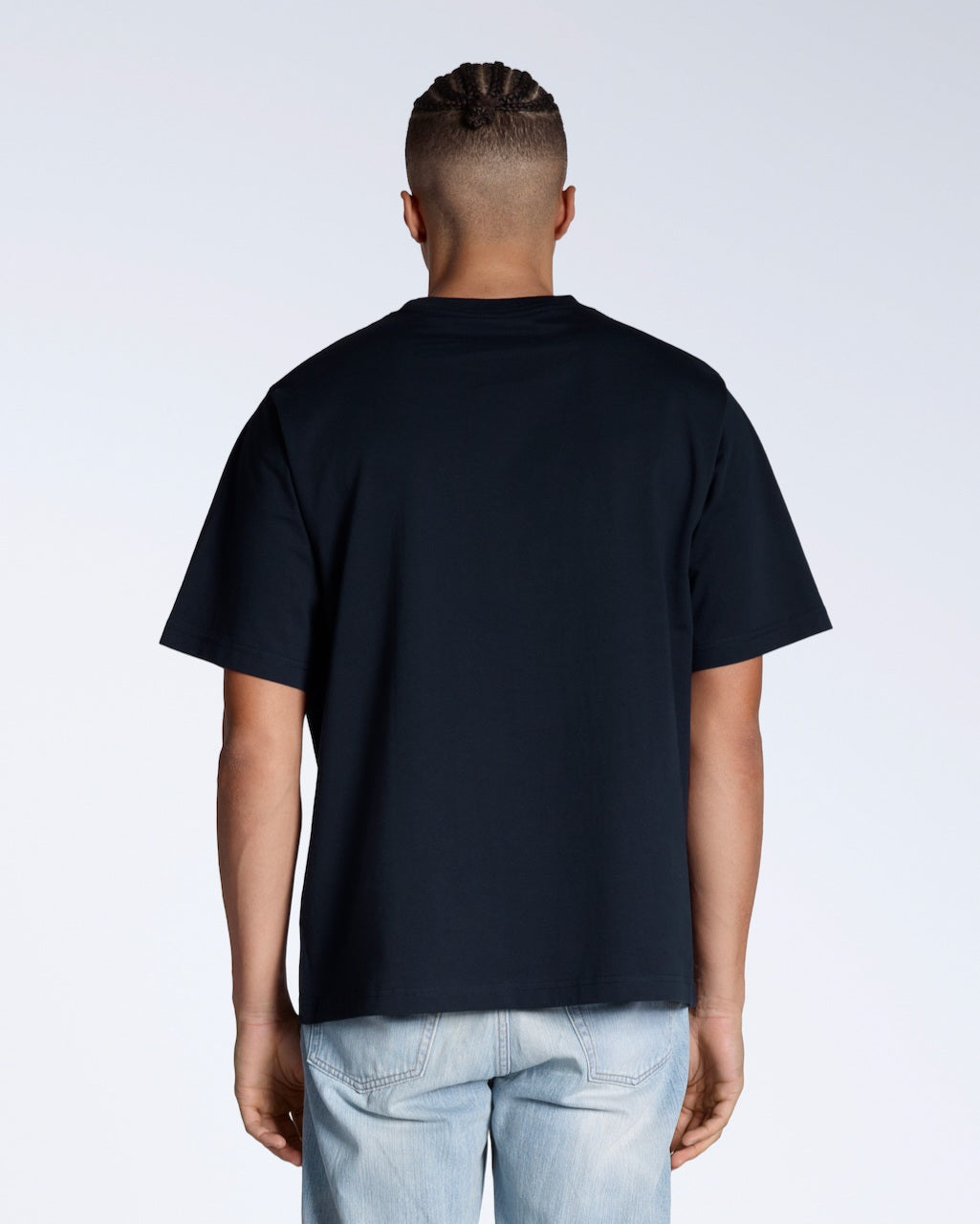 A man facing away from the camera, modelling a plain navy, oversized, organic cotton t shirt.