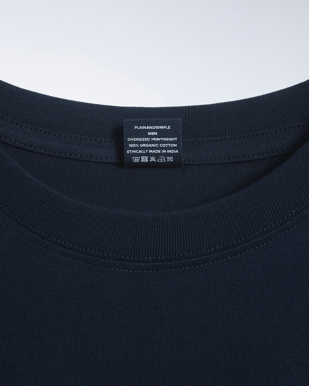A close up of a neck label in a men's navy, oversized heavyweight, organic cotton t shirt.
