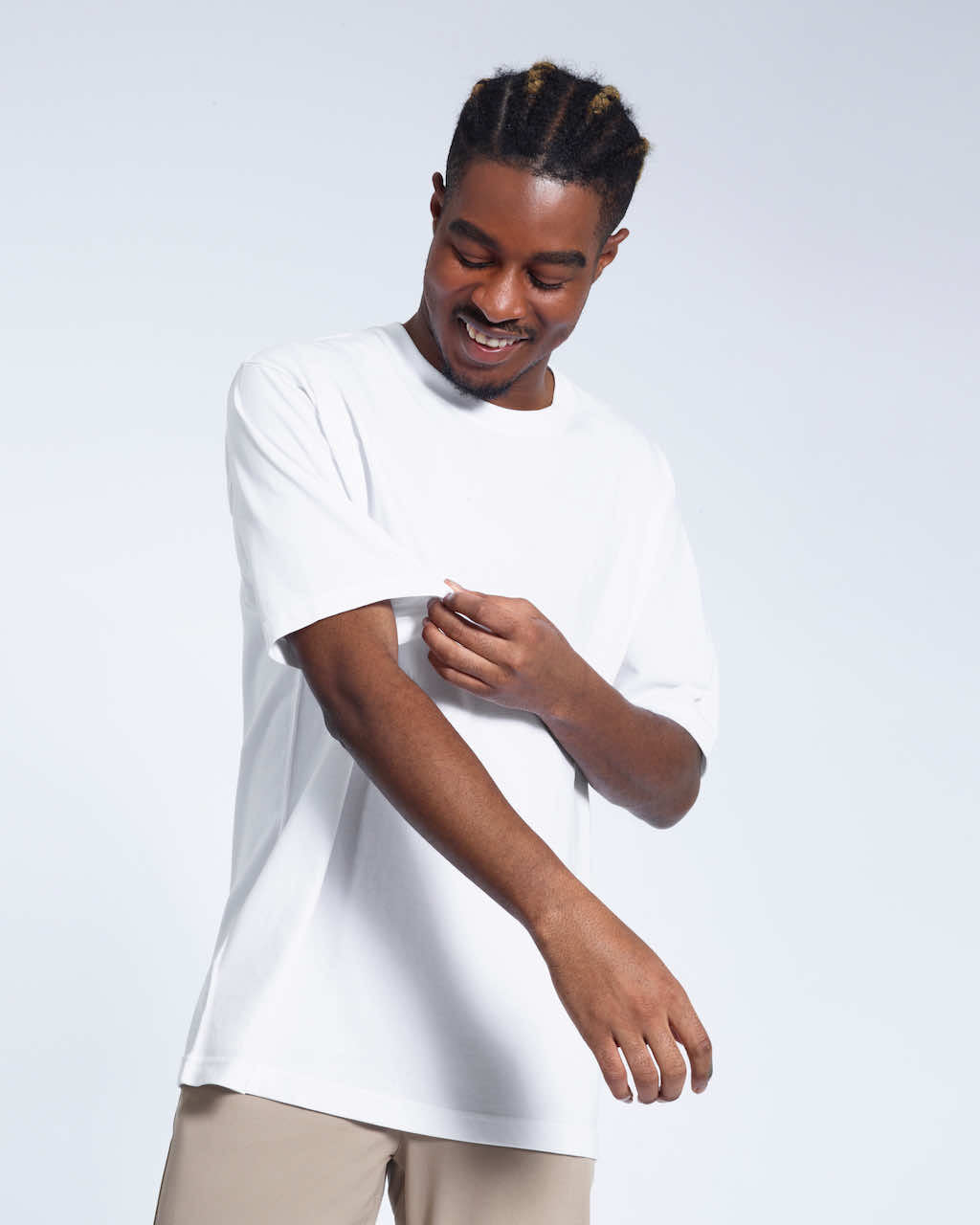 A man looking down and touching his sleeve, modelling a plain white oversized heavyweight organic cotton t shirt.