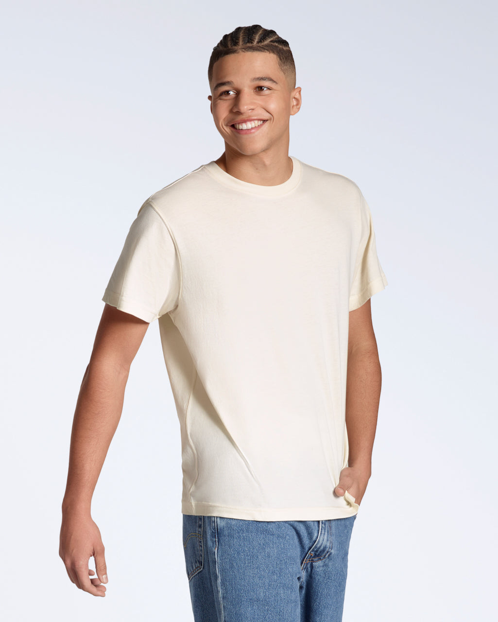 A man smiling with his hand in his pocket, modelling a plain, natural coloured, organic cotton t shirt.