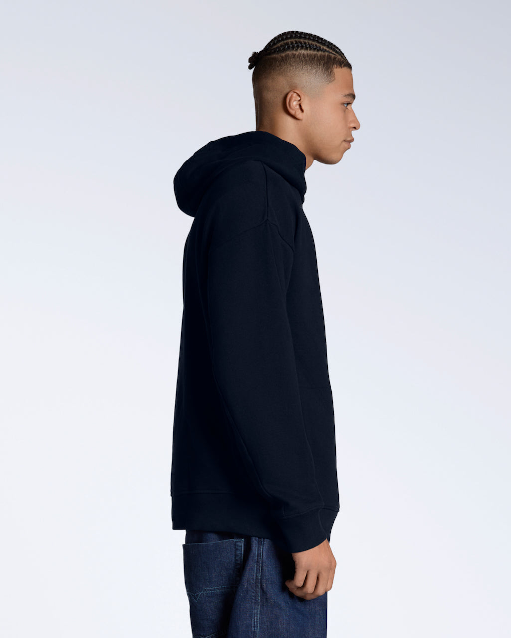A man facing side on, modelling a navy oversized organic cotton hoodie.