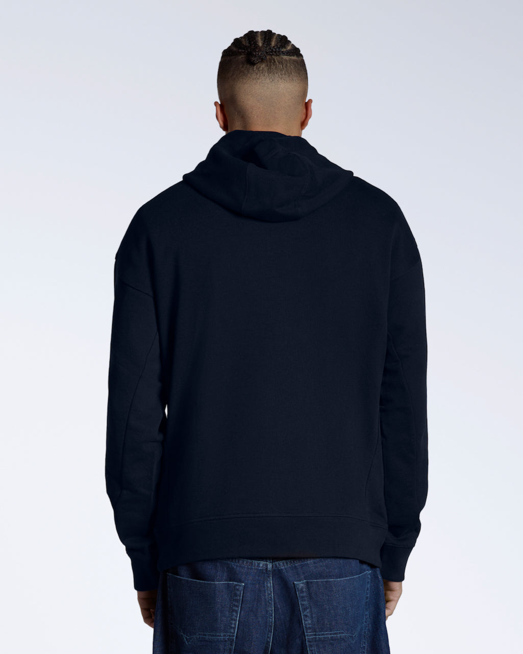 A man facing away from the camera with his arms by his sides, modelling a navy oversized organic cotton hoodie.