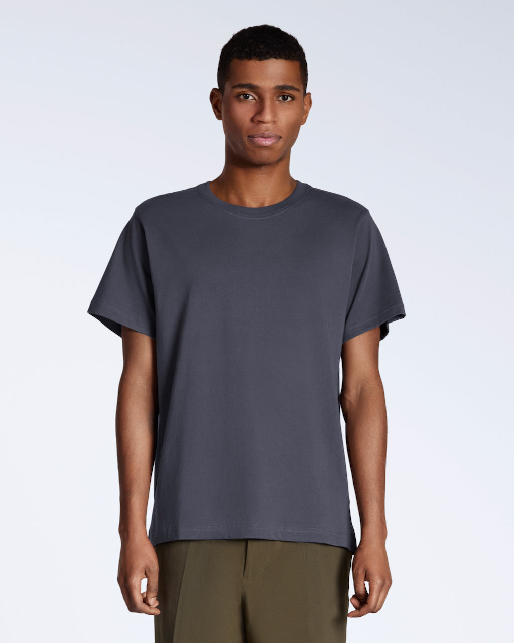 A man facing front on looking into the camera, modelling a plain dark grey, organic cotton t shirt.