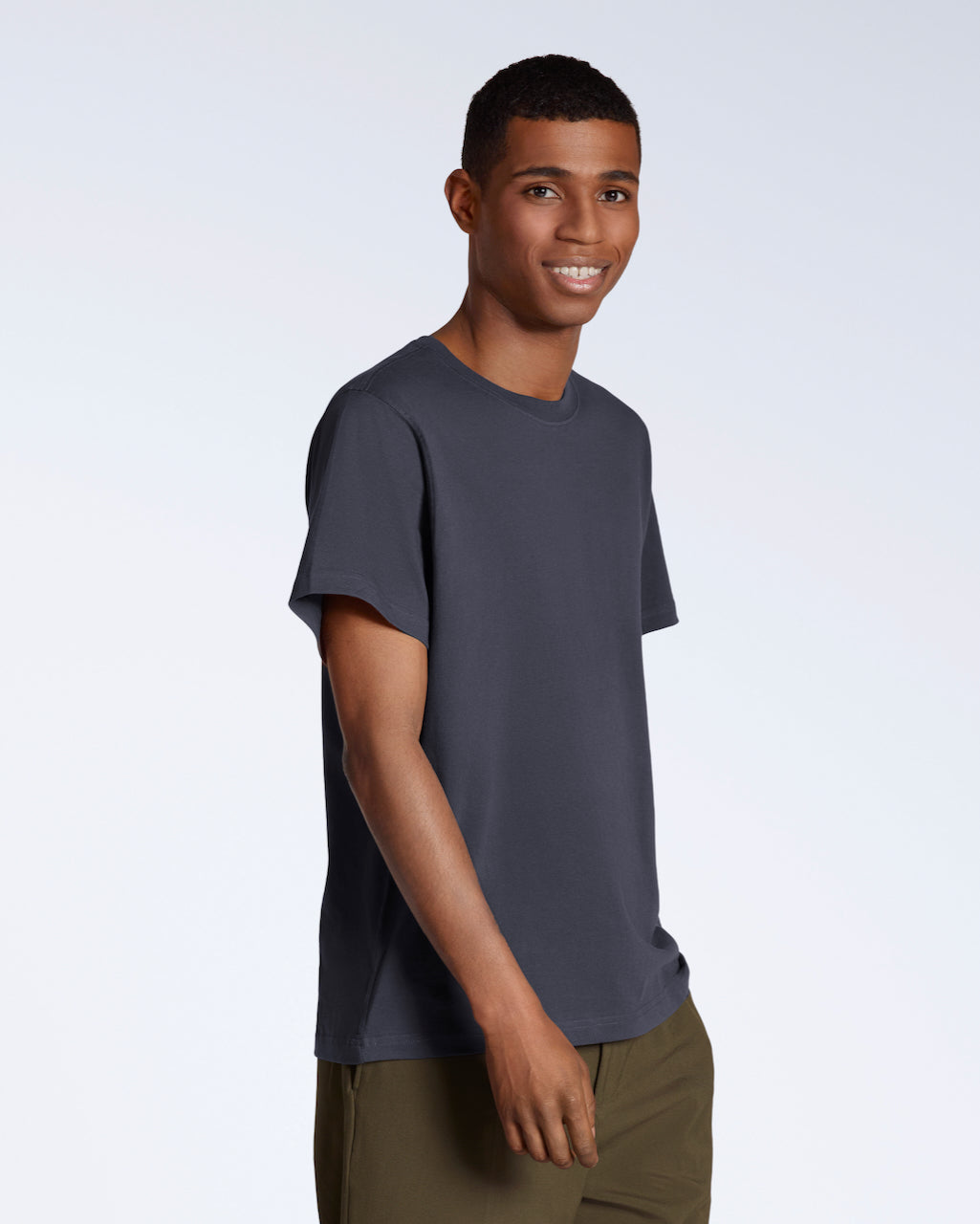 A man smiling into the camera, modelling a plain dark grey, organic cotton t shirt.