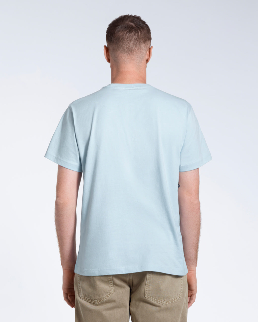 A man facing away from the camera, modelling a plain blue short sleeve organic cotton t shirt.