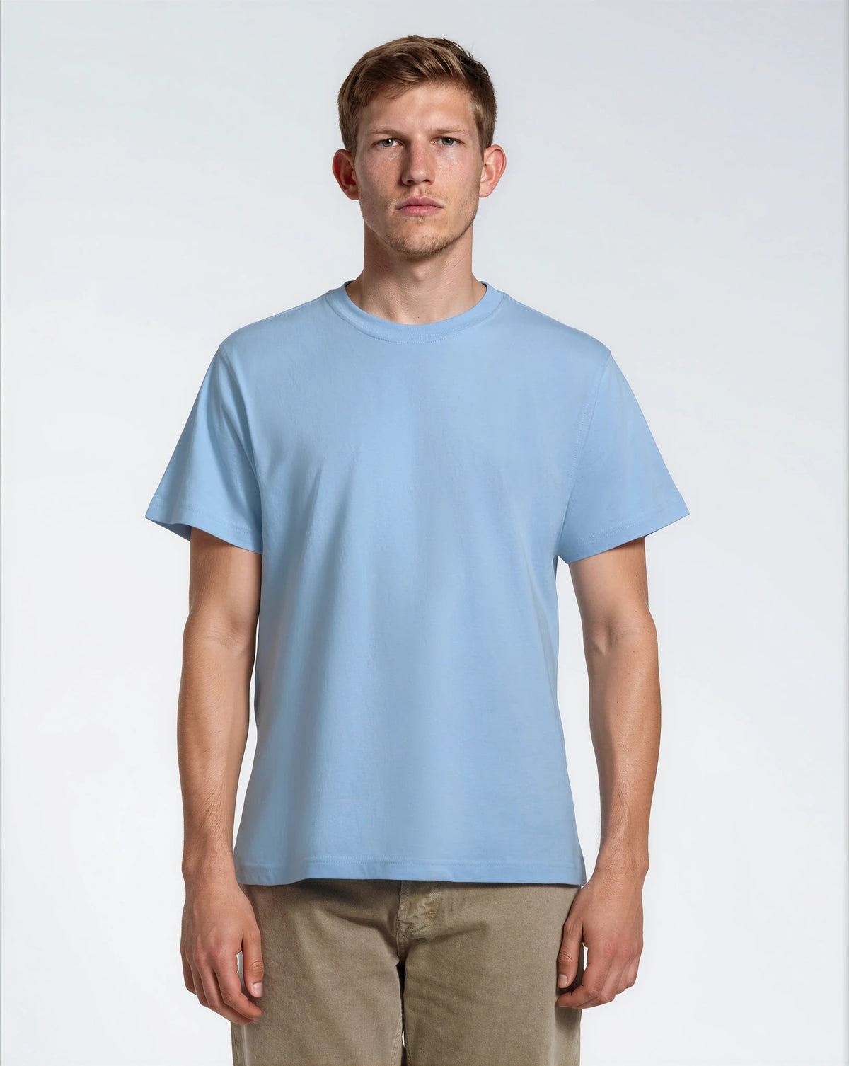A man facing front on looking into the camera, modelling a plain blue, organic cotton t shirt.
