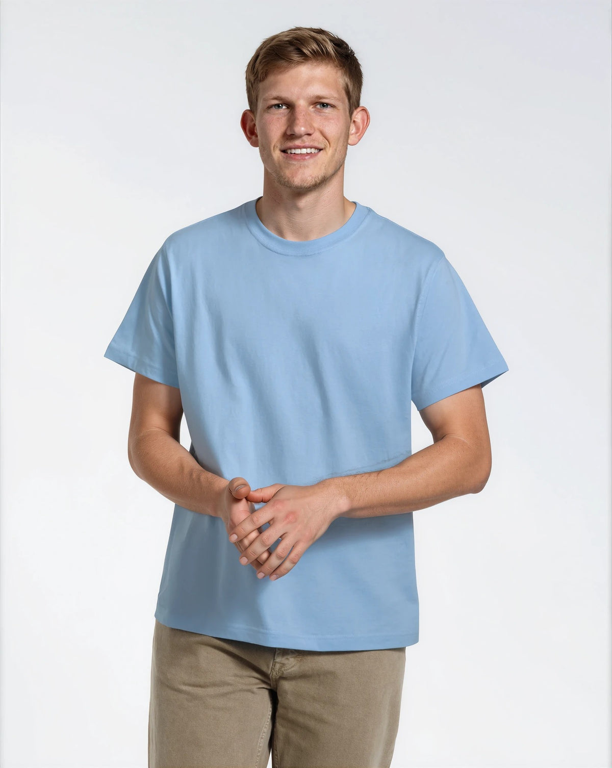 A man smiling into the camera, modelling a plain blue, organic cotton t shirt.