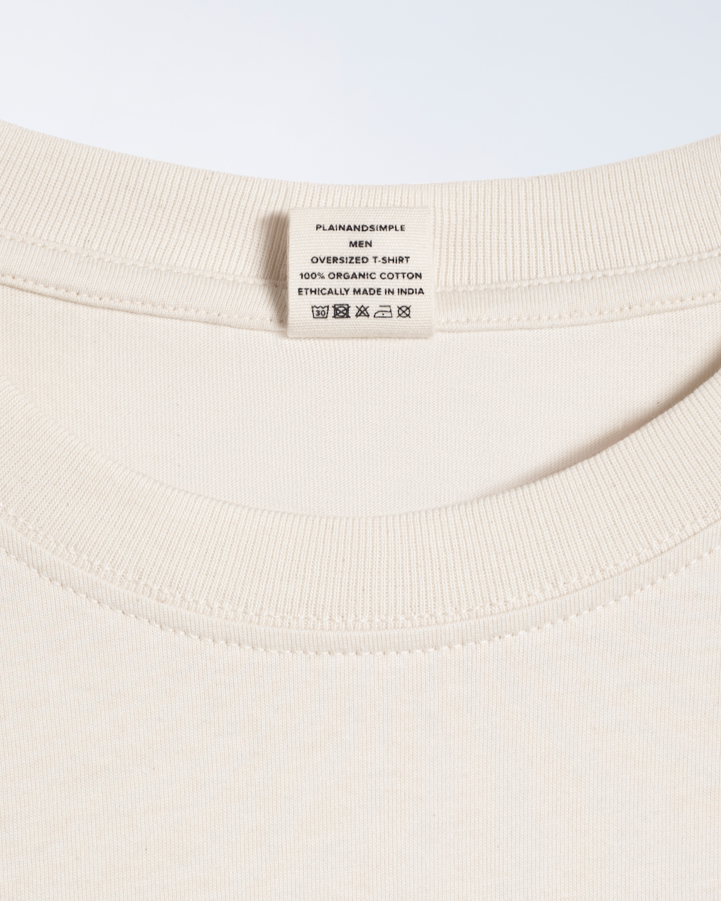 A close up of the neck label in a natural coloured, oversized, premium weight, organic cotton t shirt.