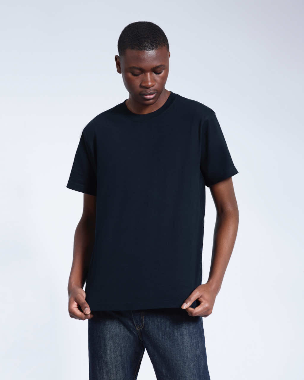 A man looking down, modelling a plain navy short sleeve organic cotton t shirt.