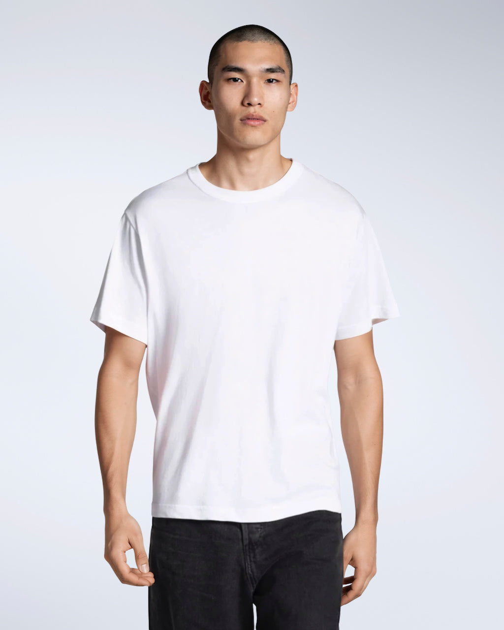 A man looking into the camera, modelling a plain white, organic cotton t shirt.