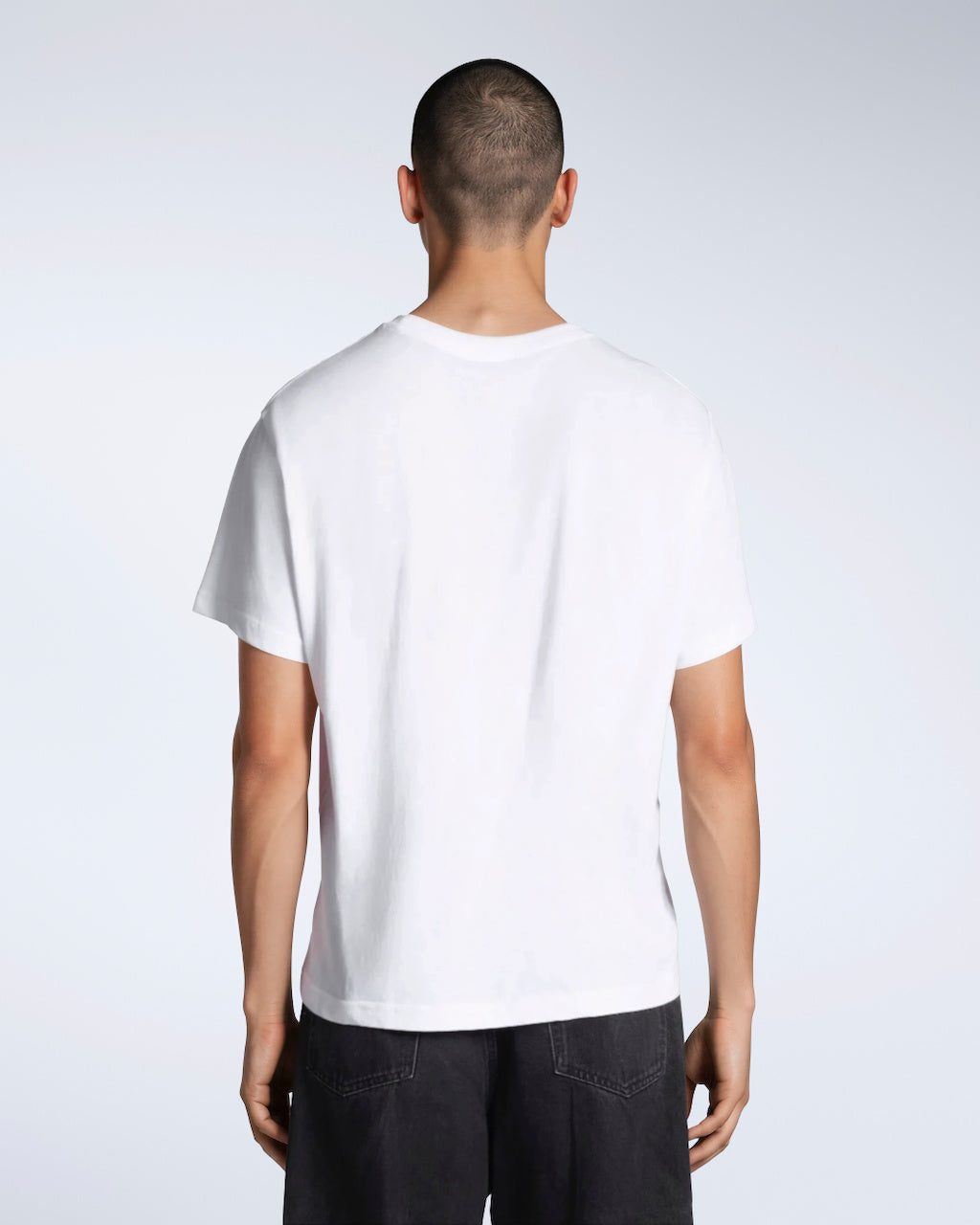 A man facing away from the camera, modelling a plain white short sleeve organic cotton t shirt.
