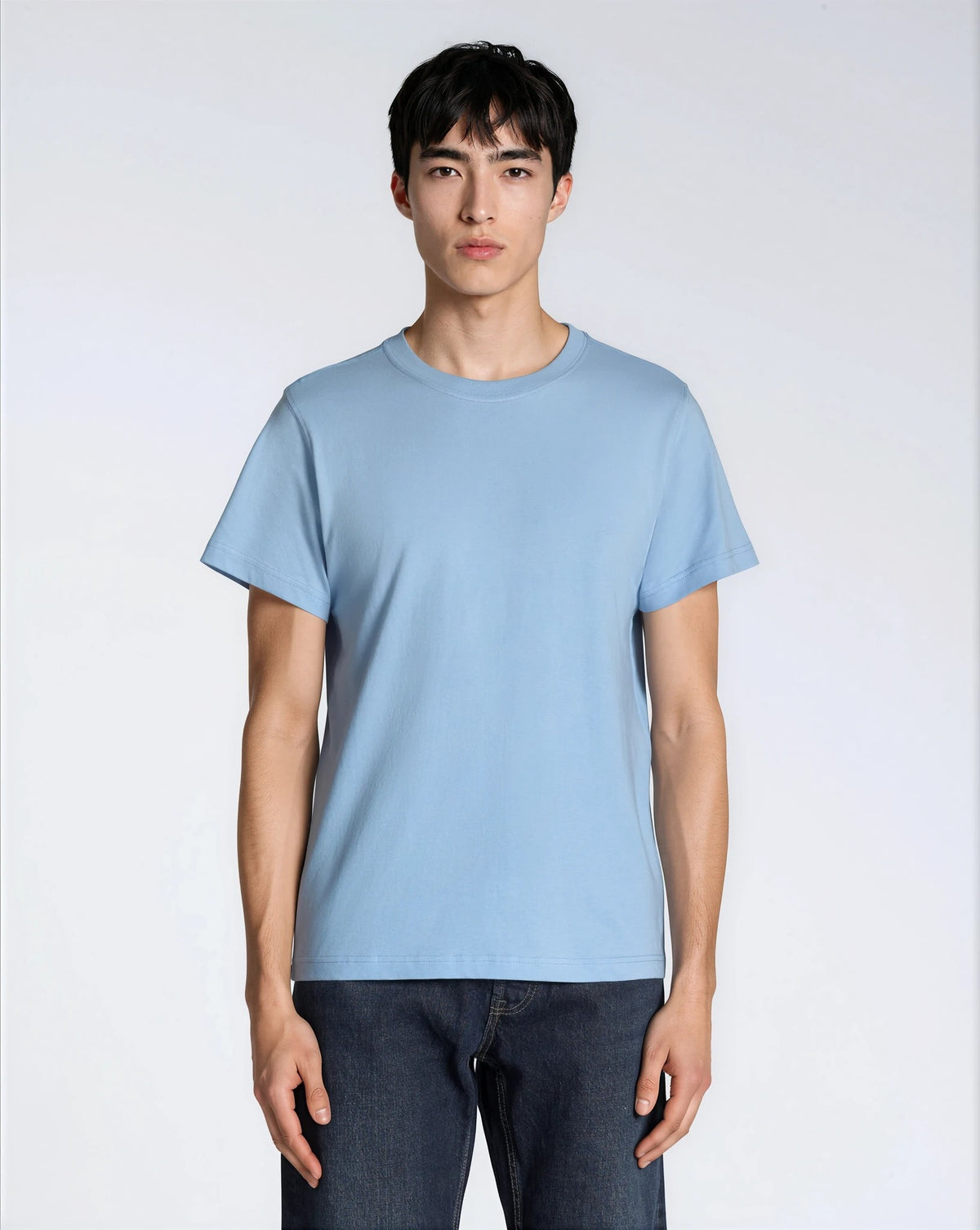 A man facing front on looking into the camera, modelling a plain blue, organic cotton t shirt.