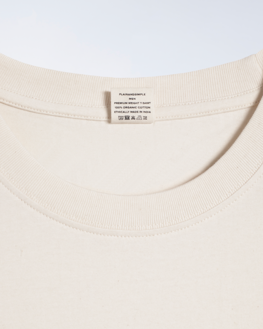 A close up of the neck label in a natural coloured, premium weight, organic cotton t shirt.