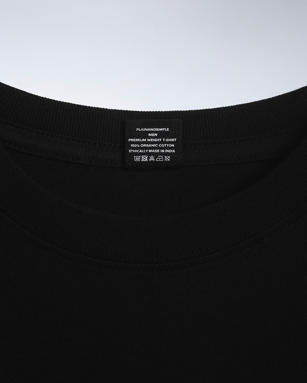 A close up of an neck label in a men's black short sleeve crew neck organic cotton t shirt.