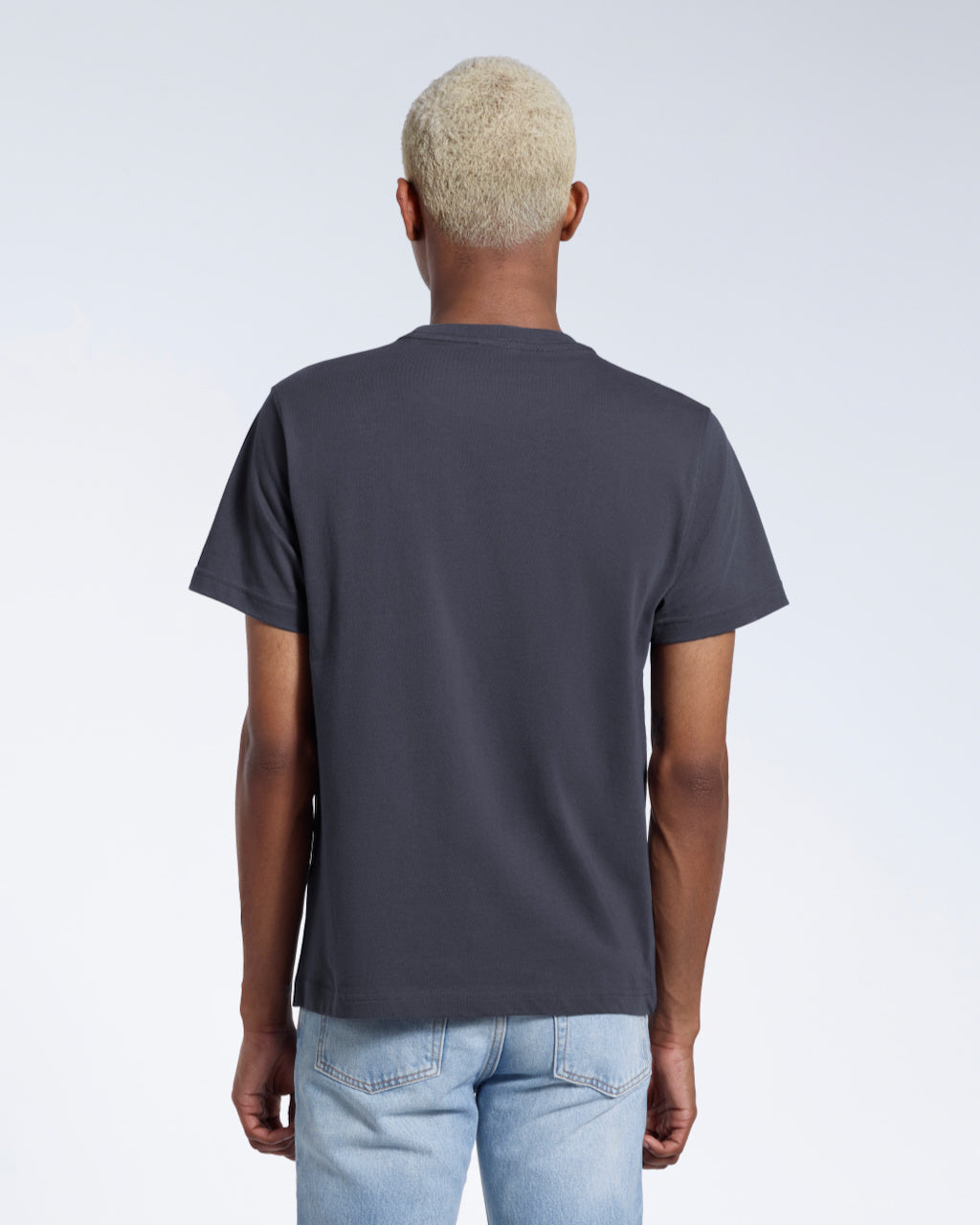 A man facing away from the camera, modelling a plain dark grey short sleeve organic cotton t shirt.
