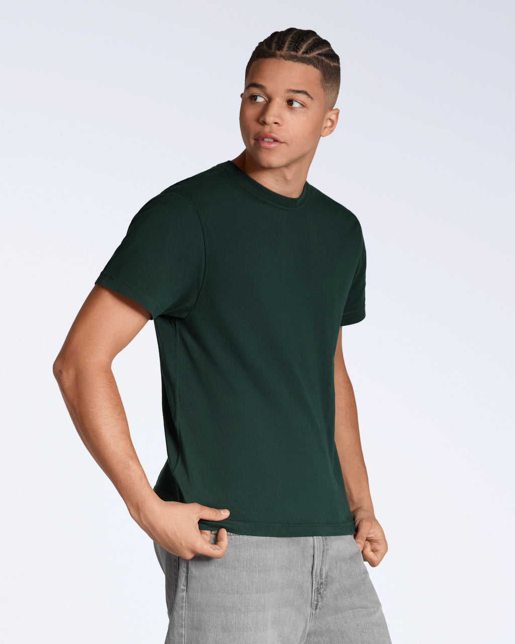 A man looking away from the camera, modelling a plain green, organic cotton t shirt.