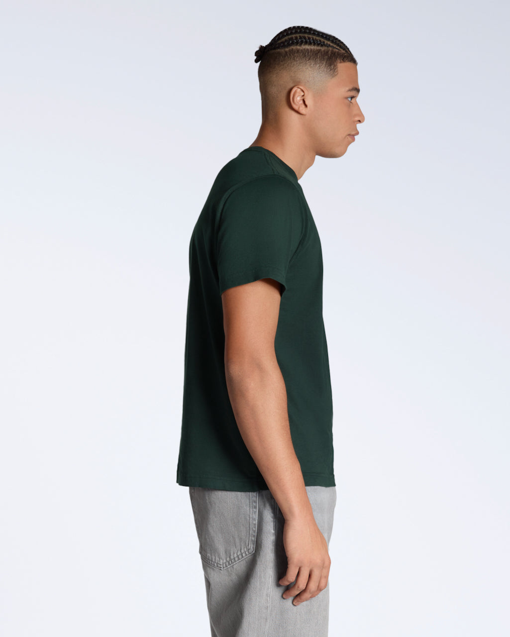 A man facing side on, modelling a plain green, short sleeve organic cotton t shirt.
