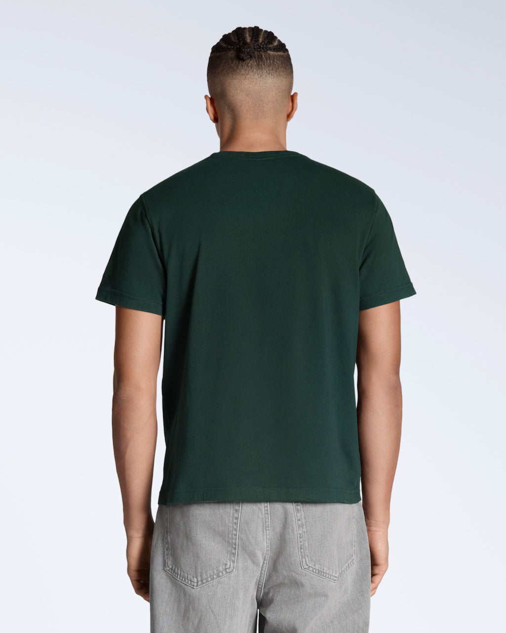 A man facing away from the camera, modelling a plain green, short sleeve organic cotton t shirt.