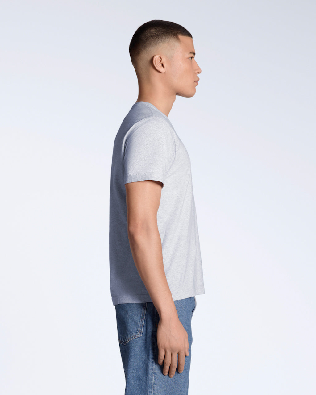A man facing side on, modelling a plain grey short sleeve organic cotton t shirt.