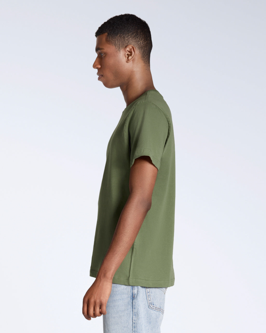 A man facing side on, modelling a plain khaki green short sleeve organic cotton t shirt.