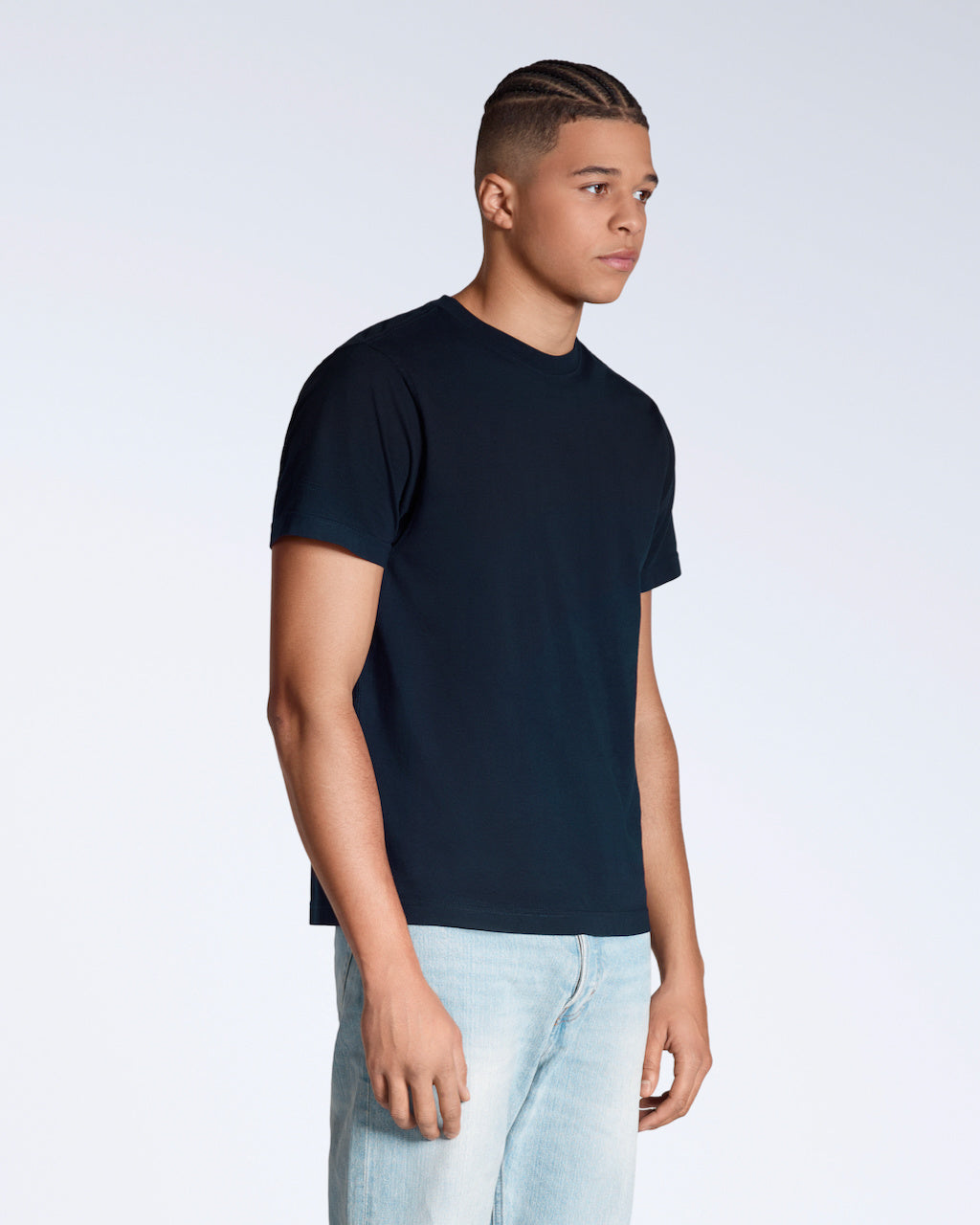 A man at an angle with his arms by his sides, modelling a plain navy short sleeve organic cotton t shirt.